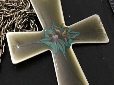 Sale Photo Thumbnail #146: Vintage enamel cross pendant necklace featuring a flared cross design with hand-painted style enamel detail in turquoise, pink, and gold tones over an olive-tan background. The chain clasp is marked CELEBRITY. The pendant measures approximately 3 inches i