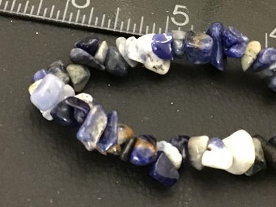 Sale Photo Thumbnail #133: Elastic stretch bracelet featuring polished blue, white, and grey natural stone chips, likely sodalite or lapis. Measures approximately 2.5 inches across unstretched. Good pre-owned condition with no visible damage.