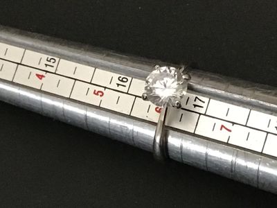 Sale Photo Thumbnail #217: A sterling silver solitaire ring featuring a large round brilliant cut clear stone (likely cubic zirconia or simulated diamond) in a four-prong setting. The interior band is stamped "S925". Shown on a ring mandrel as a size 6. In good pre-owned condition 