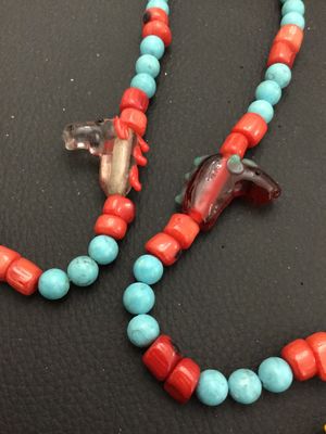 Sale Photo Thumbnail #4: Unique beaded strand necklace featuring turquoise-colored and red coral-tone beads interspersed with blown/cast glass horse head charms. Features a focal drop with a glass horse head, large red bead, and a stamped metal cross pendant. Includes a metal tog