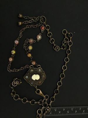 Sale Photo Thumbnail #262: A vintage brass-tone chain belt featuring a central ornate pendant set with a portrait cameo insert and surrounding multi-color cabochon accents. The chain strand includes additional bezel-set multi-colored faux stones and a hook clasp closure with decora