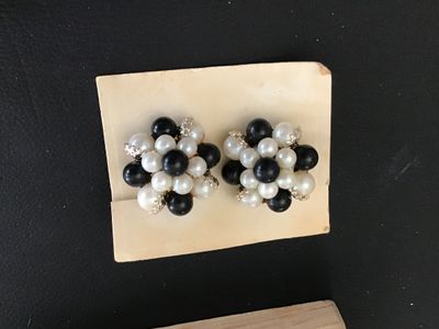 Sale Photo Thumbnail #72: Pair of vintage cluster clip-on earrings featuring a mix of black and white faux pearls in gold-tone metal filigree settings. Mounted on original display card stamped 'MADE IN JAPAN'. Clips are intact and functional. Minor age-appropriate wear visible.