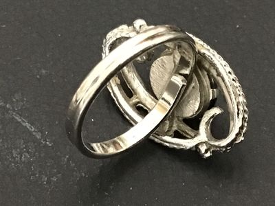 Sale Photo Thumbnail #109: Vintage Sarah Coventry silver-tone costume ring featuring a dark oval cabochon stone (hematite style) set within an ornate, textured swirl motif setting. Marked ©SARAH COV on the inner band. Features an adjustable band construction. Good vintage conditio