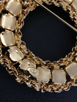 Sale Photo Thumbnail #27: A vintage gold-tone circle/wreath brooch by Hobe featuring faux pearls set within an intricate braided chain border. Signed 'Hobe' on an oval plaque on the reverse. Measures approximately 1.75 inches in diameter. Secure pin back closure with safety clasp.