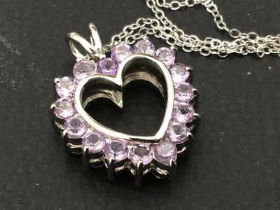 Sale Photo Thumbnail #143: A sterling silver heart-shaped pendant necklace featuring a reversible design. One side is adorned with multi-color round faceted gemstones including amethyst, peridot, citrine, garnet, and blue topaz, while the reverse side features a halo of uniform lig