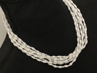 Sale Photo Thumbnail #169: Vintage multi-strand statement necklace featuring white rice/oval-shaped molded  glass beads. Finished with decorative gold-tone filigree end caps and an adjustable hook closure with extension chain. Marked 'JAPAN' on the hook clasp. In good vintage condi