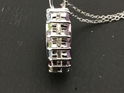 Sale Photo Thumbnail #141: A sterling silver heart-shaped pendant necklace featuring a reversible design. One side is adorned with multi-color round faceted gemstones including amethyst, peridot, citrine, garnet, and blue topaz, while the reverse side features a halo of uniform lig