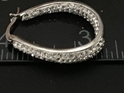 Sale Photo Thumbnail #95: Pair of silver-tone oval hoop earrings set with clear pavé rhinestones/crystals. Features latch-back closures. Earrings measure approximately 1 inch in length as shown against the scale. Good pre-owned condition with all stones intact.