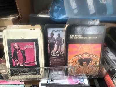 Sale Photo Thumbnail #64: Collection of classic rock 8-track tapes in a clear plastic rack, including albums by Tom Petty and the Heartbreakers, The Doors, and Jimi Hendrix and a bunch more 