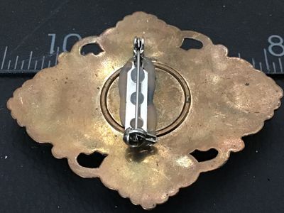 Sale Photo Thumbnail #40: Vintage brooch pin featuring a silver-tone/pewter-style woman's portrait cameo set in an ornate bronze-tone Faux metal frame with scrolling openwork design. The reverse shows a glued-on bar pin back mechanism. Measures approximately 2 inches tall by 1.5 i