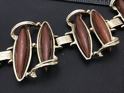 Sale Photo Thumbnail #99: Mid-century vintage gold tone link bracelet set with brown/caramel lucite or resin navette cabochons. Features sculpted scroll-like metalwork and a fold-over clasp. Measures approximately 7 inches in length. In good vintage condition with minor surface we