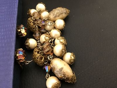 Sale Photo Thumbnail #70: Pair of vintage gold-tone clip-on dangle earrings featuring aurora borealis rhinestones, faceted crystal beads, filigree caps, and dangling faux pearls. Overall in good vintage condition with clip backs intact; some light finish wear and aging on central 
