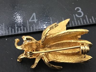 Sale Photo Thumbnail #77: A detailed vintage gold-tone textured insect brooch featuring a fly or bee design. The piece features spring-mounted (trembler) wings that move and clear rhinestone accents embellishing the head and wing bases. Secured with a standard rollover clasp. Meas