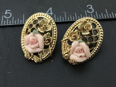Sale Photo Thumbnail #79: Pair of gold-tone oval pierced stud earrings featuring an openwork lattice filigree design detailed with gold flowers and a central dimensional light pink porcelain rose with green leaves. Each earring measures approximately 1 inch in length. Complete wit
