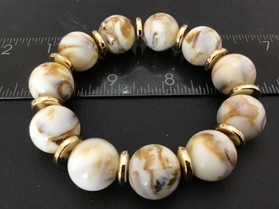 Sale Photo Thumbnail #52: A stretch beaded bracelet featuring marbled cream and light brown swirled round beads separated by gold-tone disc spacers. The bracelet measures approximately 2.5 to 3 inches in outer diameter.