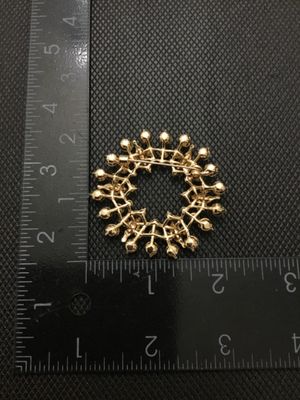 Sale Photo Thumbnail #216: A vintage gold-tone circular wreath brooch or pin, encrusted with round clear rhinestones and featuring leaf-like textured accents with embedded stones. Measures approximately 2 inches in diameter. Features a rollover safety clasp on the back. Appears to 