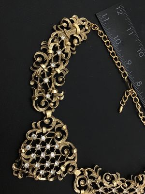 Sale Photo Thumbnail #4: A vintage Jose Barrera for Avon gold-tone collar statement necklace featuring intricate filigree scrollwork set with clear rhinestones. Includes an adjustable hook closure with an extender chain. Hallmarked 'Barrera for Avon' on the back. The necklace mea