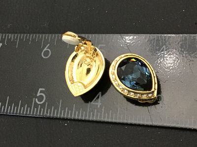 Sale Photo Thumbnail #112: Pair of vintage gold-tone clip-on earrings featuring large teardrop-cut dark blue crystal center stones surrounded by a halo of clear rhinestones. Features comfort pads on the clip backs. Measures approximately 3/4 inch in length. Items show light wear co