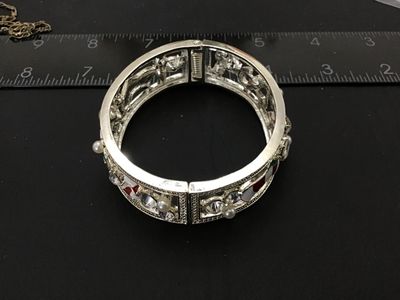 Sale Photo Thumbnail #186: Silver-tone hinged cuff bangle bracelet featuring holiday-themed enamel motifs including Christmas stockings and candy canes, accented with clear rhinestones and imitation pearls. Measures approximately 2.5 inches in diameter with a spring hinge closure. 
