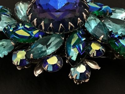 Sale Photo Thumbnail #139: Vintage Judy Lee costume jewelry brooch featuring vibrant blue, aqua, and green aurora borealis marquis cut and round faceted glass rhinestones prong-set in silver-tone metal. Measures approximately 3 inches wide. Features a filigree back setting with sta