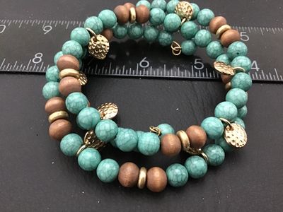 Sale Photo Thumbnail #145: Boho-style multi-row coil wrap bracelet featuring simulated turquoise crackle beads, natural wooden beads, and small hammered gold-tone coin-style charms. Flexible wire coil construction accommodates most wrist sizes. Good condition with no visible damage