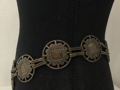 Sale Photo Thumbnail #155: Vintage brass-tone chain link belt featuring ornate openwork circular medallions inset with purple and brown glass or acrylic cabochons. Includes an adjustable hook and tail extension chain. Shows light finish wear and patina consistent with age.