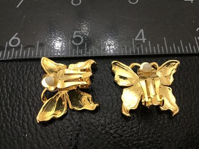 Sale Photo Thumbnail #193: Pair of gold-tone clip-on earrings shaped like butterflies, featuring light and dark blue enamel accents and small clear rhinestones. Each earring measures approximately 1 inch across. Clip-on backs are functional with soft pads intact. Good pre-owned con