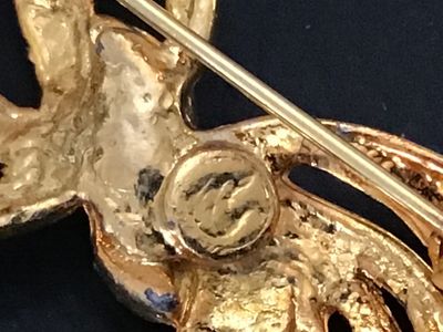 Sale Photo Thumbnail #43: A vintage gold-tone costume jewelry brooch designed as an abstract ribbon or spray bow. Features a silver-tone central band set with clear rhinestones. Shows light finish wear on the back and minor surface wear consistent with age. Measures approximately 