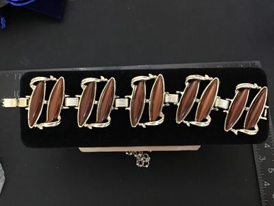 Sale Photo Thumbnail #97: Mid-century vintage gold tone link bracelet set with brown/caramel lucite or resin navette cabochons. Features sculpted scroll-like metalwork and a fold-over clasp. Measures approximately 7 inches in length. In good vintage condition with minor surface we