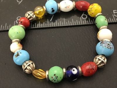 Sale Photo Thumbnail #13: Multicolor beaded stretch bracelet featuring artisan-style art glass beads in various colors (blue, green, red, yellow, white, and evil eye motif) separated by textured silver-tone spacer beads. Measures approximately 7 to 7.5 inches in circumference. App