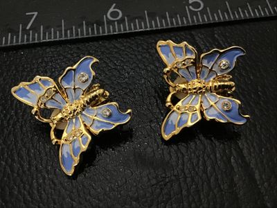 Sale Photo Thumbnail #191: Pair of gold-tone clip-on earrings shaped like butterflies, featuring light and dark blue enamel accents and small clear rhinestones. Each earring measures approximately 1 inch across. Clip-on backs are functional with soft pads intact. Good pre-owned con