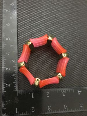 Sale Photo Thumbnail #242: Fashion stretch bracelet featuring vibrant pink and orange acrylic curved links separated by polished gold-tone spacer beads. Measures approximately 3 inches in outer diameter. In good pre-owned condition with light surface wear.