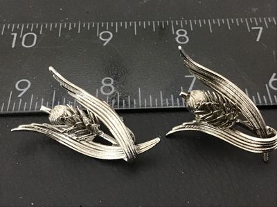 Sale Photo Thumbnail #61: Pair of vintage silver-tone clip-on earrings featuring a botanical design of wheat stalks and acorns. Clip-on backs are in good working condition. Each earring measures approximately 1.5 inches in length.