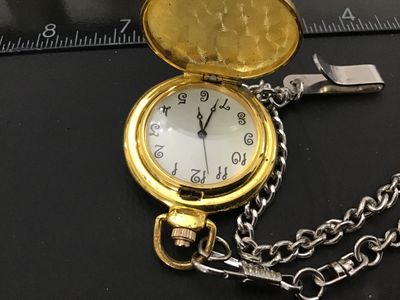 Sale Photo Thumbnail #203: Gold-tone hunter case pocket watch featuring a winter scene with a cardinal on the front cover and an ornate, detailed pattern on the back cover. The white dial displays unique, decorative stylized numerals. Includes a silver-tone chain with a belt clip. 