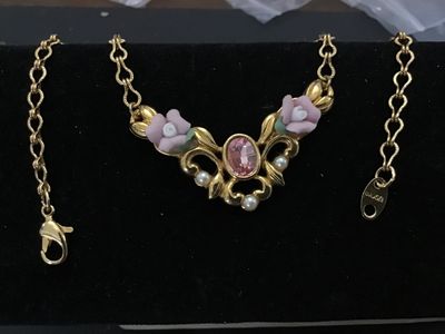 Sale Photo Thumbnail #195: Vintage Avon gold-tone necklace featuring a ornate scrollwork centerpiece with pink porcelain roses, green leaf accents, faux pearl details, and a central pink oval crystal stone. Signed Avon on the back of the pendant and on the hangtag. Fitted with a lo