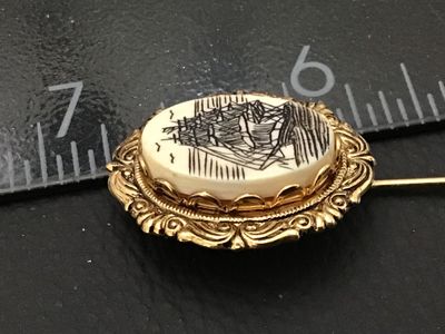 Sale Photo Thumbnail #22: Vintage stick pin featuring an oval cabochon with a scrimshaw-style illustration of a tall sailing ship surrounded by birds. Set in a gold-tone ornate filigree frame. Includes a protective pin guard end cap. Overall pin length measures approximately 2.5 i