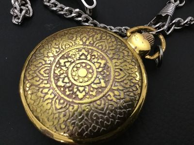 Sale Photo Thumbnail #201: Gold-tone hunter case pocket watch featuring a winter scene with a cardinal on the front cover and an ornate, detailed pattern on the back cover. The white dial displays unique, decorative stylized numerals. Includes a silver-tone chain with a belt clip. 