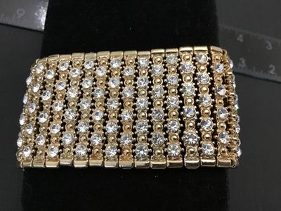 Sale Photo Thumbnail #125: Gold-tone stretch cuff bracelet featuring multiple rows of clear rhinestones. Measures approximately 1.5 inches wide with an elasticized stretch fit. Good condition with all stones intact.