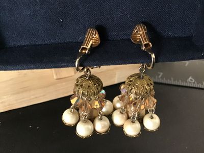Sale Photo Thumbnail #69: Pair of vintage gold-tone clip-on dangle earrings featuring aurora borealis rhinestones, faceted crystal beads, filigree caps, and dangling faux pearls. Overall in good vintage condition with clip backs intact; some light finish wear and aging on central 