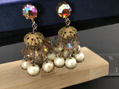 Sale Photo Thumbnail #68: Pair of vintage gold-tone clip-on dangle earrings featuring aurora borealis rhinestones, faceted crystal beads, filigree caps, and dangling faux pearls. Overall in good vintage condition with clip backs intact; some light finish wear and aging on central 