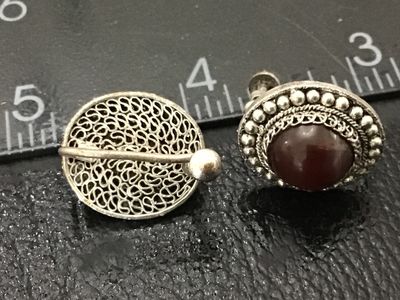 Sale Photo Thumbnail #164: Pair of vintage silver-tone screw-back earrings featuring intricate filigree work, beaded borders, and polished dark red/carnelian-style cabochon stones. Oval face measures approximately 0.75 inches long. Light patina consistent with age; overall good vin