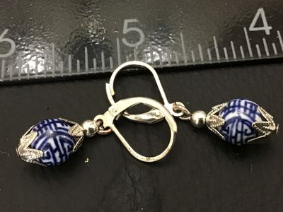 Sale Photo Thumbnail #171: Pair of dangle earrings featuring round blue and white porcelain beads with detailed geometric/Asian inspired patterns, set in silver-tone filigree metal end caps. Designed with leverback closures for secure wearing. Each earring measures approximately 1.