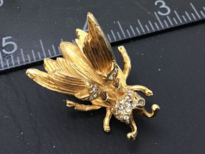Sale Photo Thumbnail #74: A detailed vintage gold-tone textured insect brooch featuring a fly or bee design. The piece features spring-mounted (trembler) wings that move and clear rhinestone accents embellishing the head and wing bases. Secured with a standard rollover clasp. Meas