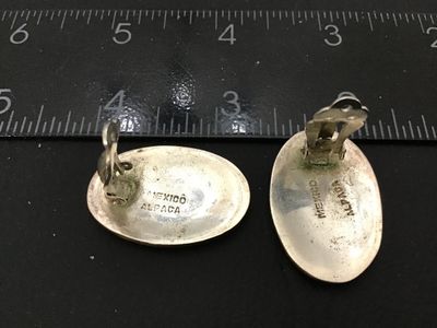 Sale Photo Thumbnail #72: Pair of vintage Mexican alpaca silver clip-on earrings featuring iridescent abalone shell center set within a cream-colored inlay border. Stamped 'MEXICO ALPACA' on the reverse. Each earring measures approximately 1.25 inches long by 0.8 inches wide. Good