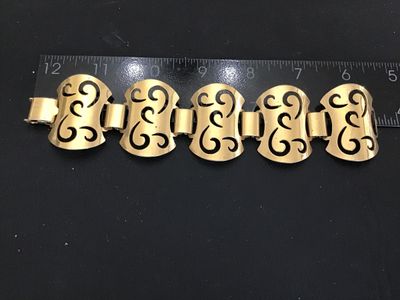 Sale Photo Thumbnail #47: Vintage Sarah Coventry gold-tone panel bracelet featuring filigree-style openwork scroll design panels connected by wide links. Marked '©SARAHCOV' on the fold-over clasp. Measures approximately 7 inches long. Shows minor surface wear and patina consisten