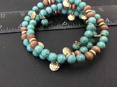 Sale Photo Thumbnail #146: Boho-style multi-row coil wrap bracelet featuring simulated turquoise crackle beads, natural wooden beads, and small hammered gold-tone coin-style charms. Flexible wire coil construction accommodates most wrist sizes. Good condition with no visible damage