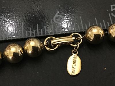 Sale Photo Thumbnail #151: A classic gold-tone sphere beaded necklace by Park Lane featuring polished metallic beads and a secure hook closure. Includes an attached 'Park Lane' logo hang tag. In good condition with bright finish and minor surface wear.