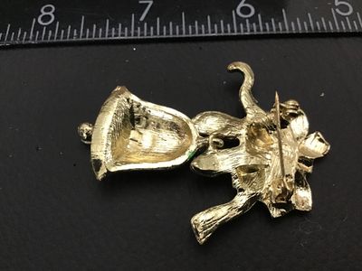Sale Photo Thumbnail #217: A festive gold-tone Christmas brooch featuring a green enamel bow and a dangling red enamel bell decorated with clear rhinestone accents. Measures approximately 2 inches long. Good vintage condition with light surface wear.