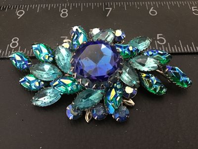 Sale Photo Thumbnail #138: Vintage Judy Lee costume jewelry brooch featuring vibrant blue, aqua, and green aurora borealis marquis cut and round faceted glass rhinestones prong-set in silver-tone metal. Measures approximately 3 inches wide. Features a filigree back setting with sta