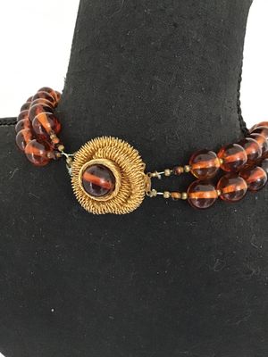 Sale Photo Thumbnail #35: Vintage multi-strand costume jewelry necklace featuring amber-tone round Lucite or resin beads with striped interior details. Includes an ornate gold-tone coiled wire centerpiece that doubles as a removable brooch/clasp piece with slide clip attachments. 